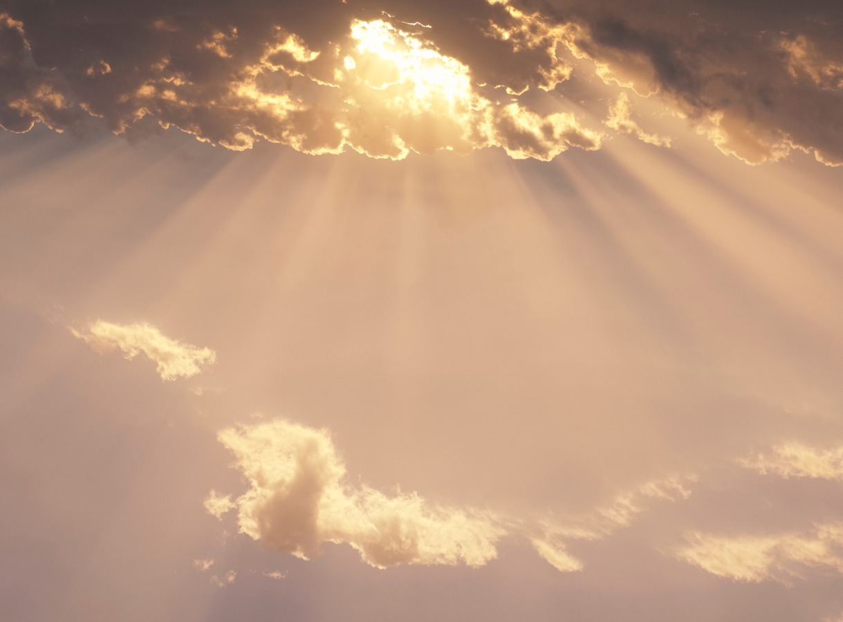 Sun rays breaking through clouds in a warm-toned sky.